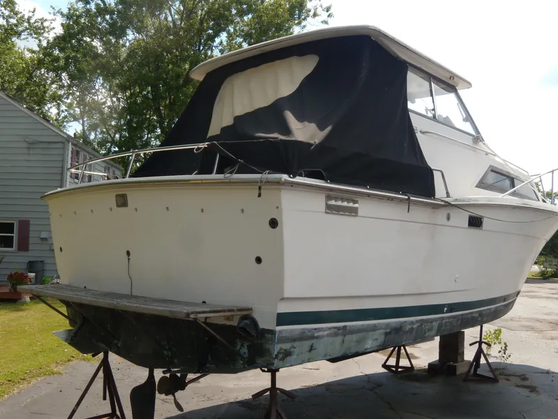 Slide: The Image of A 1973 Trojan F-32 boat on stands. It features a black canopy and a white hull. - 3