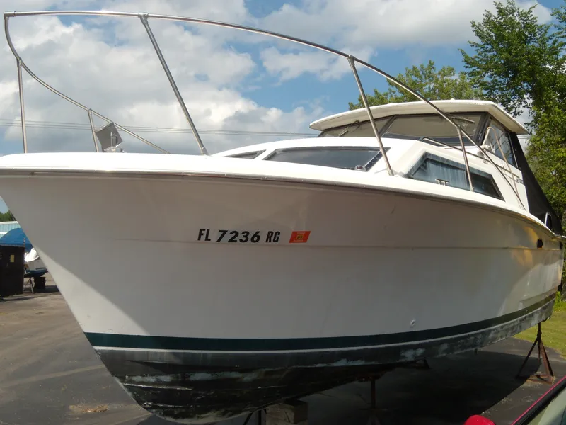 Slide: The Image of A white 1973 Trojan F-32 boat on a trailer under a cloudy sky. - 2