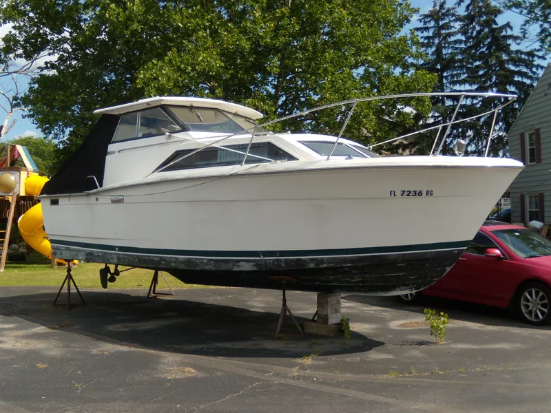 The Image of A white boat on a parking lot, featuring a black canopy and cabin. - 0