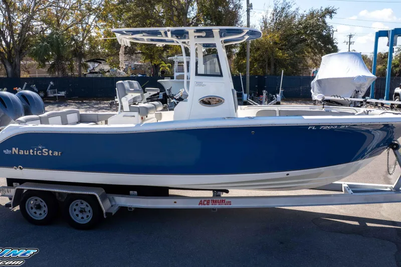 Slide: The Image of 2021 NauticStar 2602 Legacy boat on trailer, blue and white design, parked outdoors. - 44