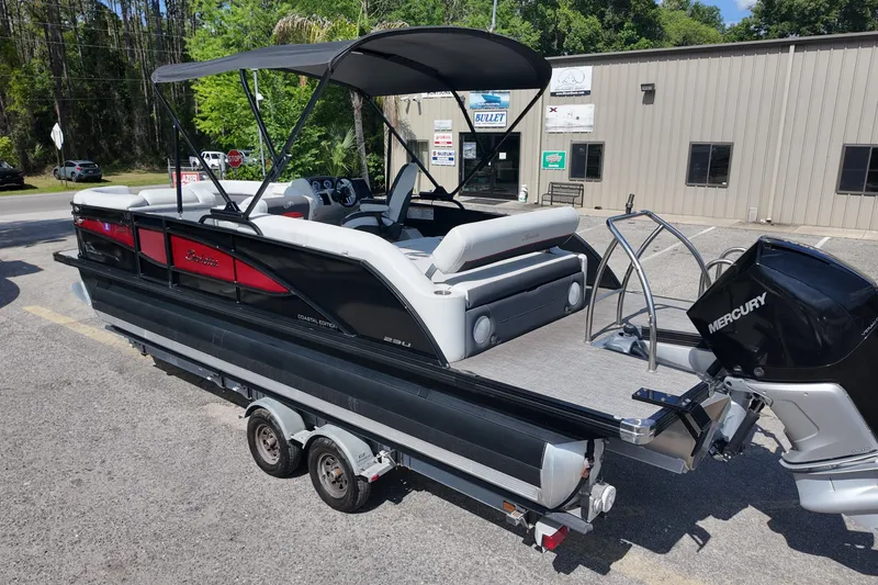 Slide: The Image of 2022 Barletta Corsa 23U pontoon boat with Mercury engine on trailer, parked outdoors. - 3