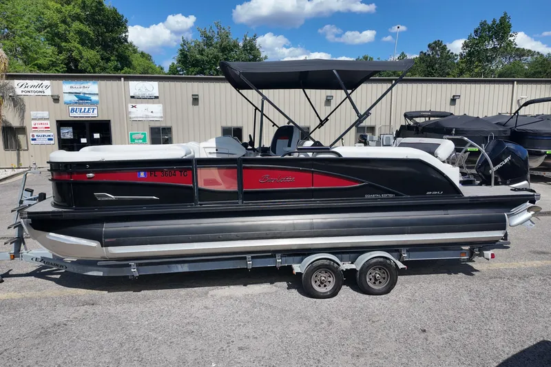 Slide: The Image of 2022 Barletta Corsa 23U pontoon boat on trailer, parked outside dealership. - 2