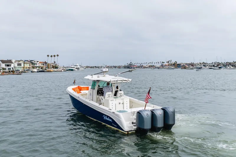 Slide: The Image of 2009 Everglades 350 Center Console boat cruising in a marina with waterfront homes. - 25