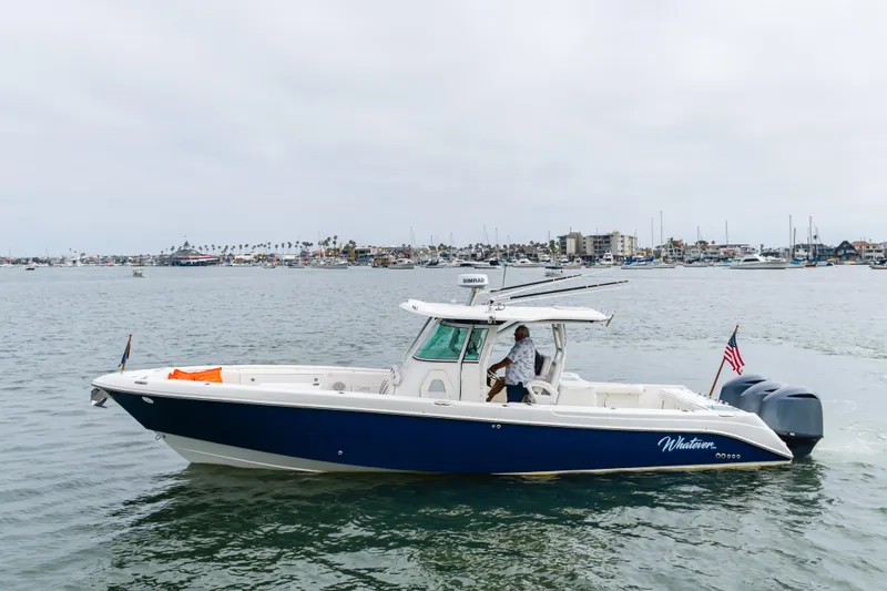 Slide: The Image of 2009 Everglades 350 Center Console boat cruising in a marina with cityscape background. - 23