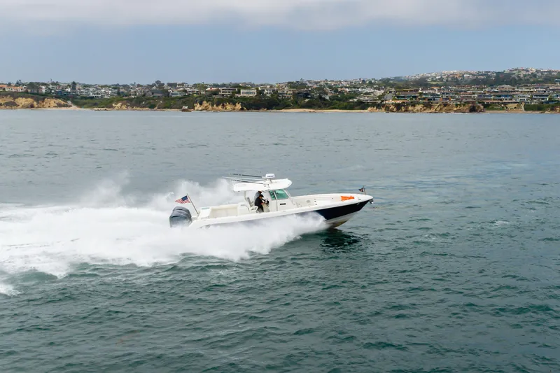 Slide: The Image of 2009 Everglades 350 Center Console boat cruising on open water near coastal landscape. - 19