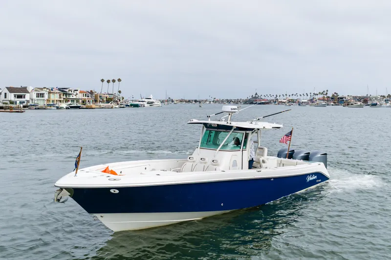 Slide: The Image of 2009 Everglades 350 Center Console boat cruising in a scenic harbor setting. - 22