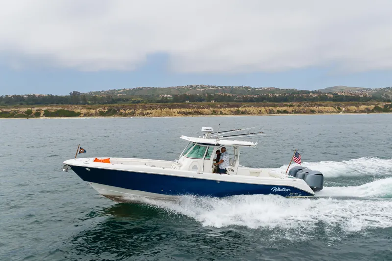 Slide: The Image of 2009 Everglades 350 Center Console boat cruising on open water near a scenic coastline. - 14