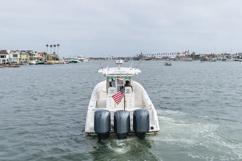Slide: The Image of 2009 Everglades 350 Center Console boat cruising in a marina with American flag. - 26