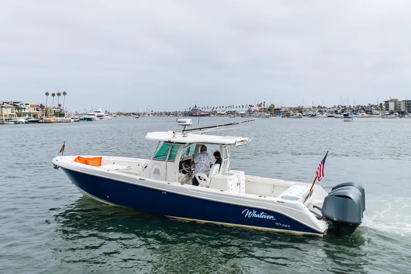 Slide: The Image of 2009 Everglades 350 Center Console boat cruising in a marina with cityscape background. - 24