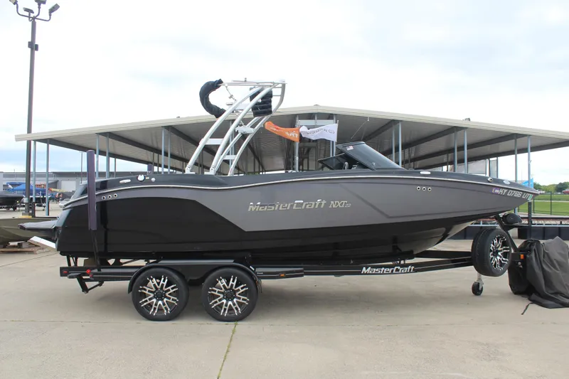 The Image of 2017 MasterCraft NXT22 boat on trailer, sleek design, parked outdoors. - 0