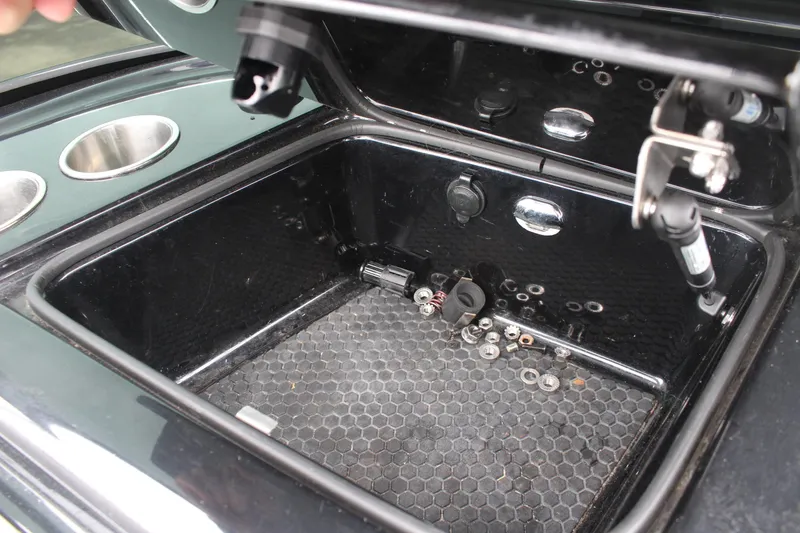 Slide: The Image of Open storage compartment in 2017 MasterCraft NXT22 boat with scattered hardware inside. - 31