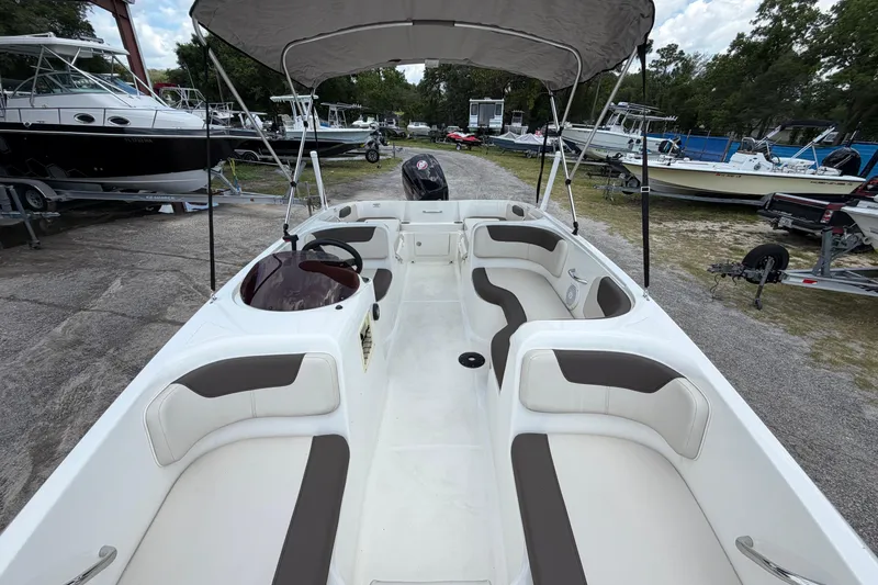 Slide: The Image of 2023 Bayliner Element E18 boat with spacious seating and canopy, parked in a marina. - 13
