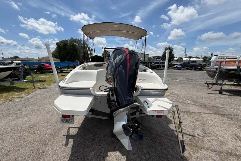 Slide: The Image of 2023 Bayliner Element E18 boat with outboard motor, parked outdoors under a sunny sky. - 2