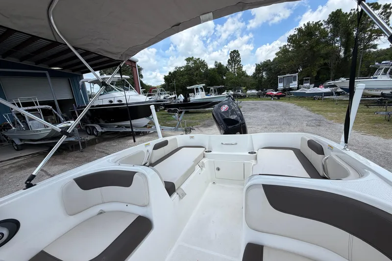 Slide: The Image of 2023 Bayliner Element E18 boat interior with seating, parked in a marina. - 12