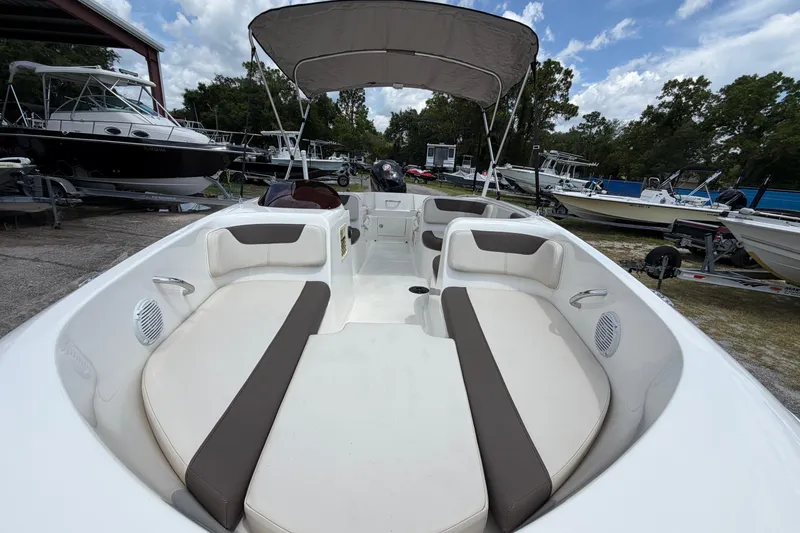 Slide: The Image of 2023 Bayliner Element E18 boat interior with seating and canopy, parked among other boats. - 5