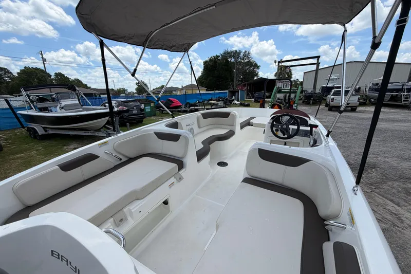 Slide: The Image of 2023 Bayliner Element E18 boat interior with seating and steering wheel under a canopy. - 10