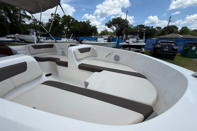 Slide: The Image of 2023 Bayliner Element E18 boat interior with cushioned seating under a blue sky. - 6