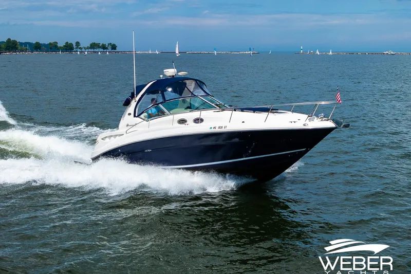Slide: The Image of 2004 Sea Ray Sundancer 320 cruising on open water with scenic shoreline in background. - 2