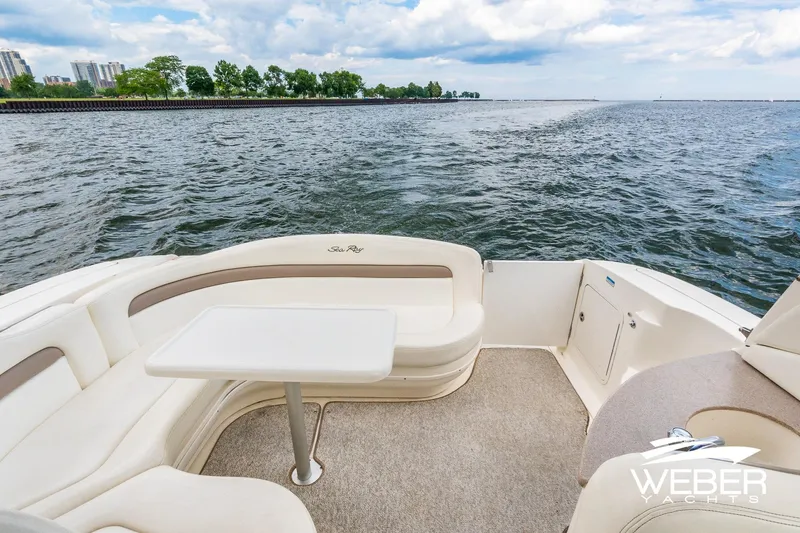Slide: The Image of 2004 Sea Ray Sundancer 320 yacht interior with seating and table, overlooking scenic waterfront. - 20