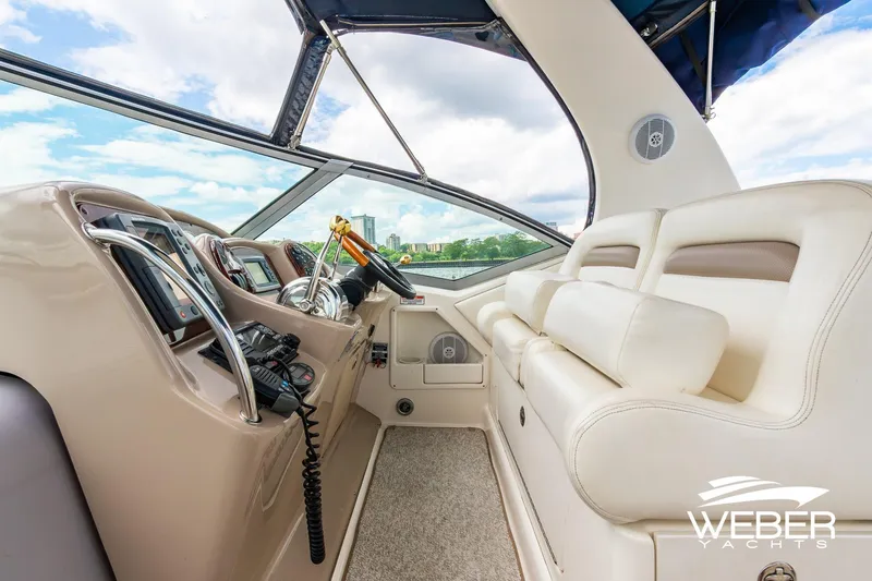 Slide: The Image of 2004 Sea Ray Sundancer 320 cockpit with plush seating and modern controls, under a clear sky. - 23