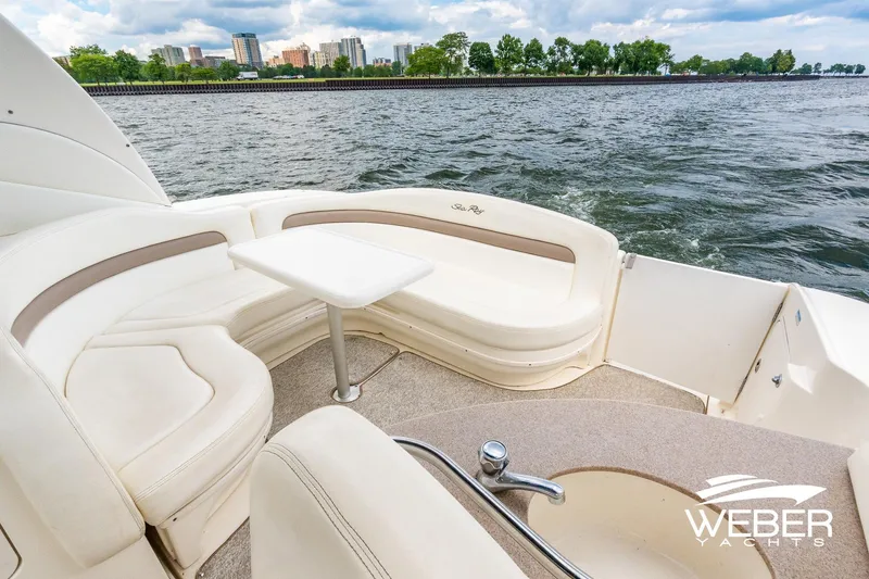 Slide: The Image of 2004 Sea Ray Sundancer 320 yacht interior with seating and table, overlooking water and cityscape. - 19