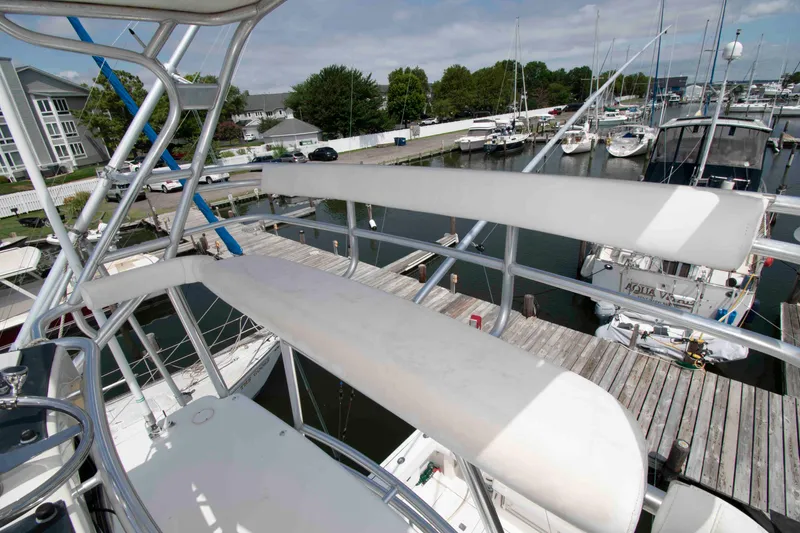 Slide: The Image of 2004 Tiara Yachts 4100 Open at marina, showcasing upper deck and docked boats. - 19