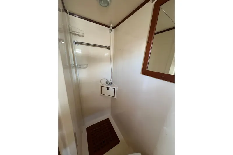 Slide: The Image of Shower area in 2007 Heritage East 36 Sundeck Trawler, featuring a mirror and wooden floor mat. - 22