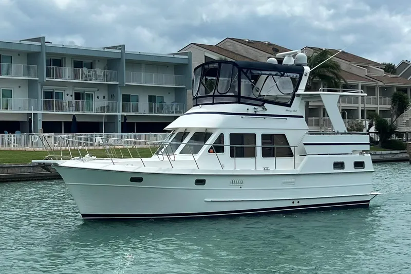 Slide: The Image of 2007 Heritage East 36 Sundeck Trawler cruising near waterfront buildings. - 2