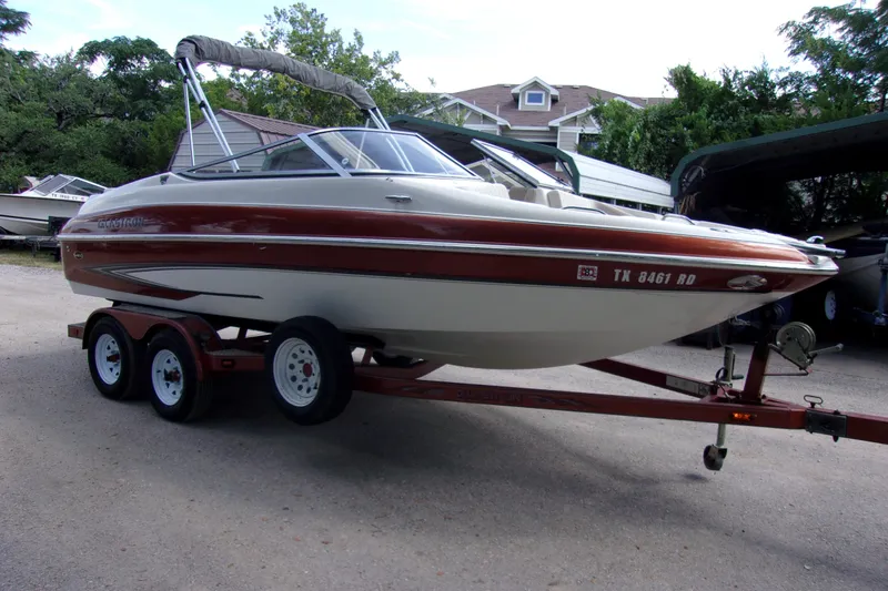 The Image of 2006 Glastron GXL 205 boat on trailer, parked outdoors with trees and houses in background. - 1