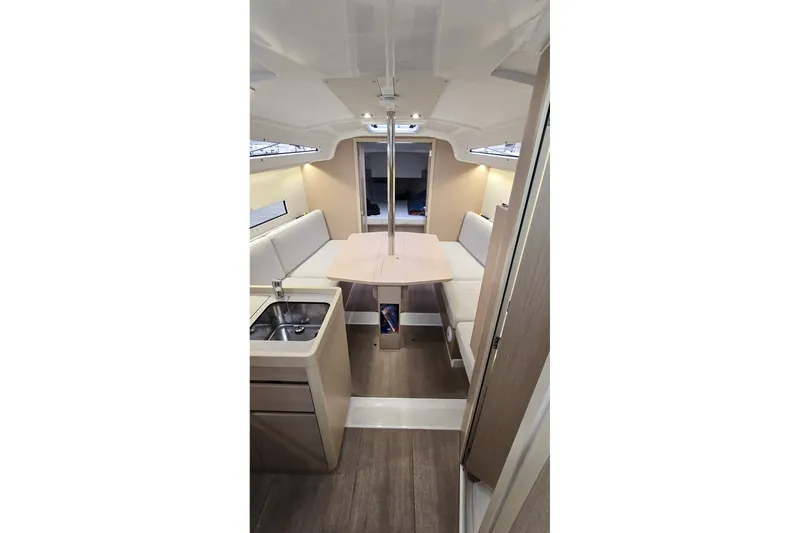 Slide: The Image of Interior of 2022 Beneteau Oceanis 30.1 yacht, featuring a cozy dining area and kitchenette. - 19