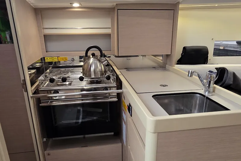 Slide: The Image of Modern kitchen area in a 2022 Beneteau Oceanis 30.1 yacht, featuring stove and sink. - 4