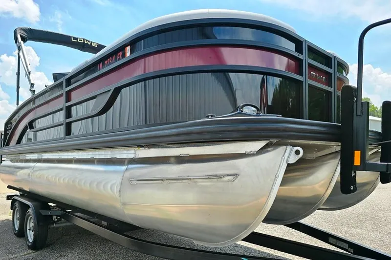 Slide: The Image of 2023 Lowe SS 210 pontoon boat on trailer under a clear blue sky. - 6