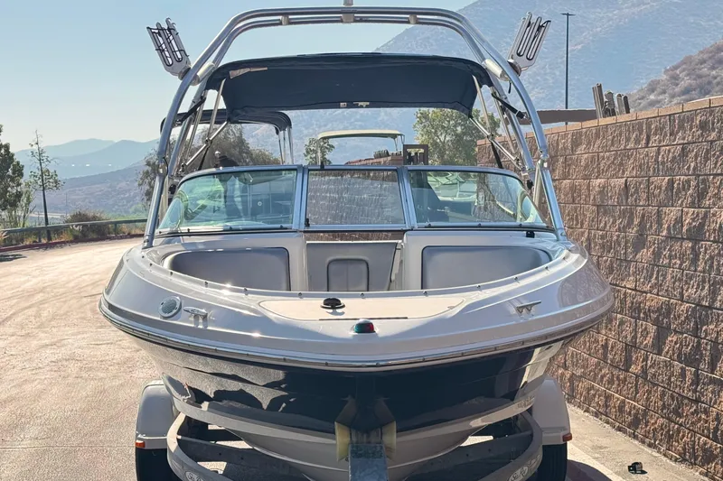 Slide: The Image of 2008 Sea Ray 205 Sport boat on trailer, parked outdoors with scenic mountain backdrop. - 2