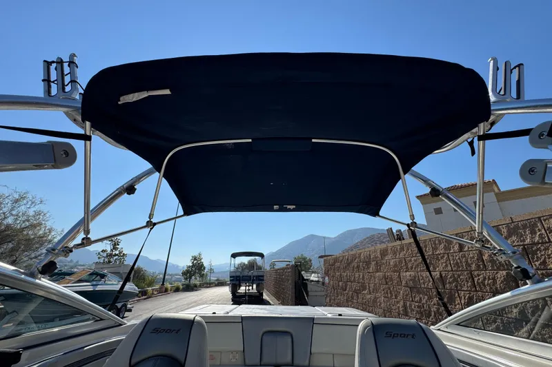 Slide: The Image of 2008 Sea Ray 205 Sport boat with bimini top, parked outdoors under clear blue sky. - 16
