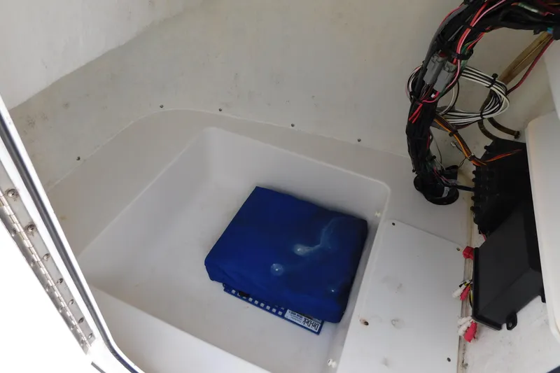 Slide: The Image of 2017 Tidewater 198 CC Adventure boat storage compartment with wiring and blue cover. - 26