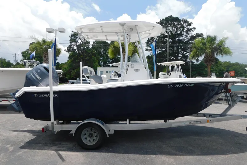 Slide: The Image of 2017 Tidewater 198 CC Adventure boat on trailer, parked outdoors with palm trees. - 17
