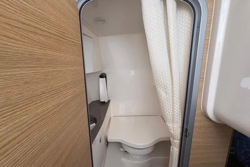 Slide: The Image of 2013 Chaparral 327 SSX boat bathroom with wood paneling and compact design. - 18