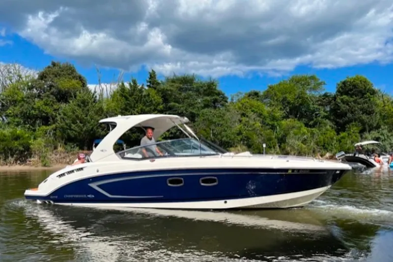 The Image of 2013 Chaparral 327 SSX boat cruising on a scenic lake under a cloudy sky. - 0