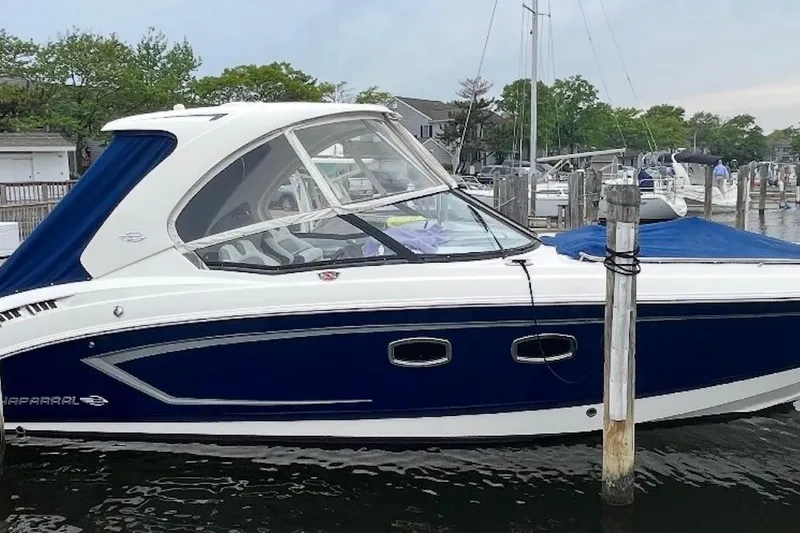 Slide: The Image of 2013 Chaparral 327 SSX boat docked, featuring sleek blue and white design. - 2