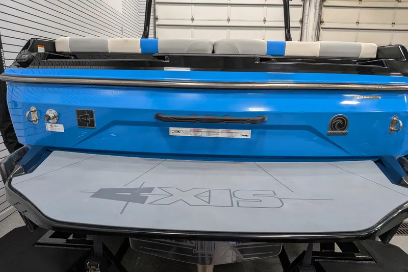 Slide: The Image of 2023 Axis A225 boat rear view, featuring blue exterior and swim platform in a garage setting. - 10