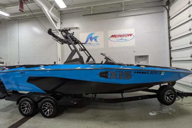 The Image of 2023 Axis A225 boat in blue and black on a trailer in a showroom. - 9