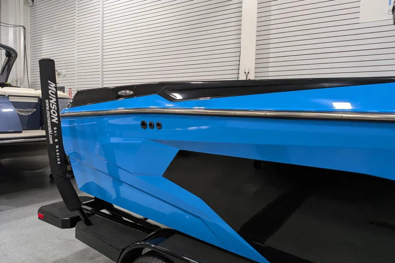 Slide: The Image of 2023 Axis A225 boat in showroom, featuring sleek blue and black design. - 12