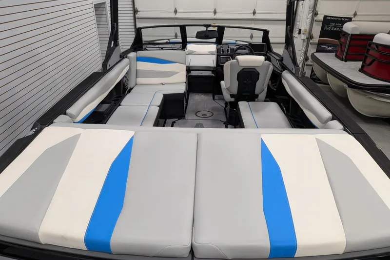 Slide: The Image of 2023 Axis A225 boat interior with gray, white, and blue seating in a garage setting. - 25