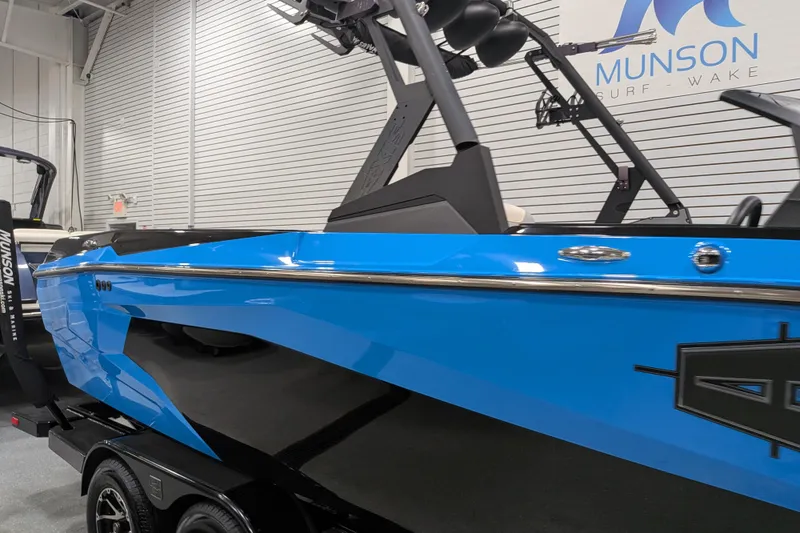 Slide: The Image of 2023 Axis A225 boat in showroom, vibrant blue and black design, Munson Surf Wake branding. - 14