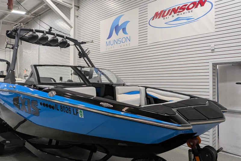 Slide: The Image of 2023 Axis A225 boat in showroom, blue and black design, Munson Ski & Marine signage. - 15