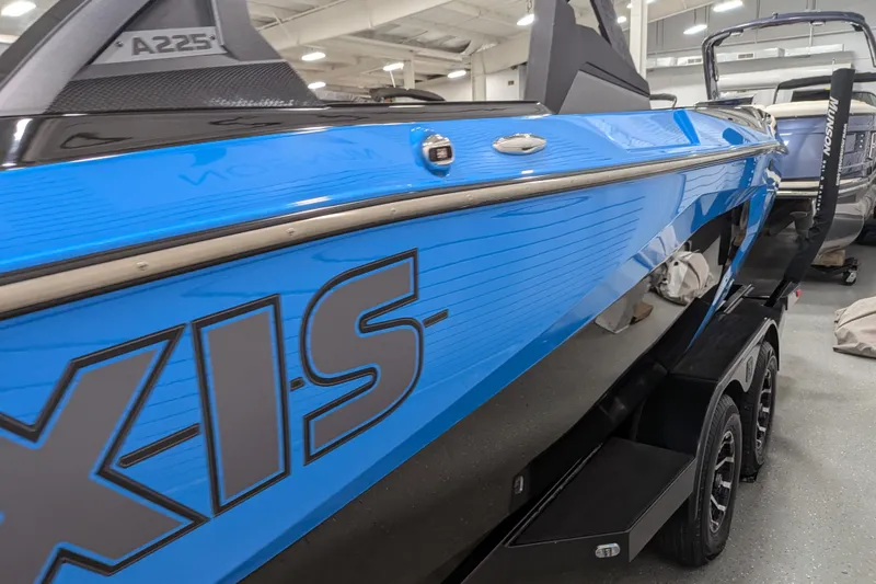 Slide: The Image of 2023 Axis A225 boat in showroom, featuring sleek blue design and modern detailing. - 19