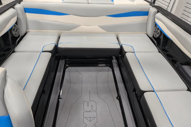 Slide: The Image of 2023 Axis A225 boat interior with gray and blue cushioned seating and integrated speakers. - 34