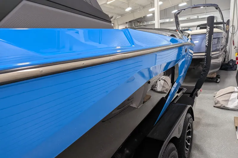 Slide: The Image of 2023 Axis A225 boat with sleek blue hull in a showroom setting. - 20
