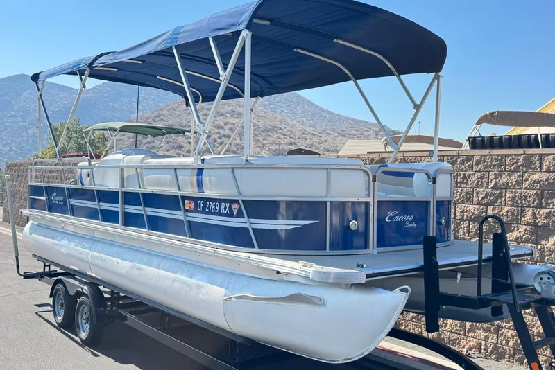 Slide: The Image of 2014 Bentley Pontoons Encore 240 Cruise on trailer, blue canopy, mountainous backdrop. - 1