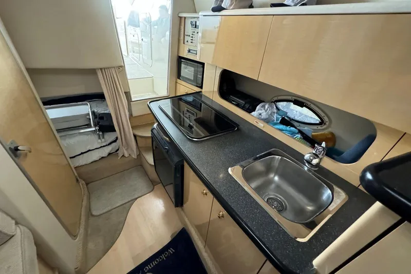 Slide: The Image of 2001 Maxum 2900 SCR boat interior with kitchenette, sink, and cozy sleeping area. - 7
